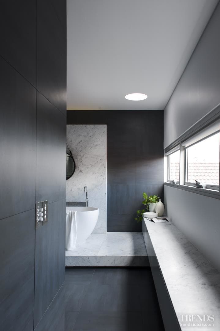 The designer chose to create a real sense of arrival to the new bathing space which is entered through the master bedroom's walk-in wardrobe. A long, low marble-topped laundry hamper which doubles as a window seat is a prelude to the generous use of Carrara marble ahead.
